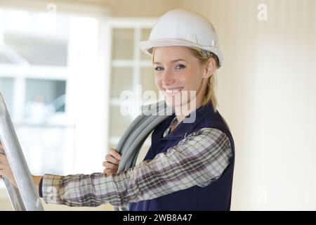 Ritratto di una donna felice su una scaletta con il trapano Foto Stock