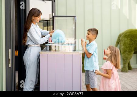 Bambina e ragazzo in attesa di un dolce zucchero di cotone al parco divertimenti Foto Stock