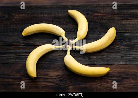 Banane su un tavolo di legno. un mazzo di banane gialle mature sul tavolo della cucina. vista dall'alto. le banane sono impilate a forma di sole, cerchio Foto Stock