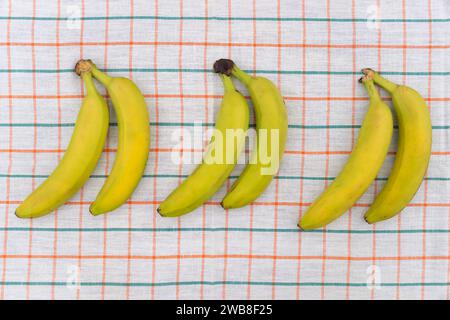 Banane gialle mature su tovaglia bianca Foto Stock