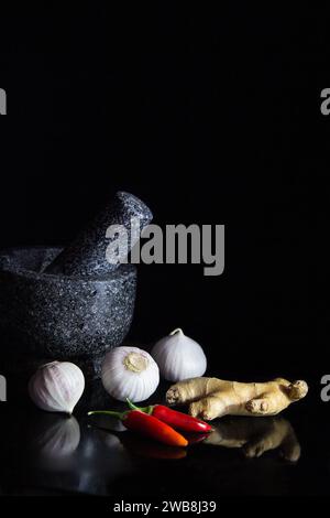 Fresh Single Clove Garlics e Malta, zenzero e peperoncino rosso su sfondo nero con riflesso Foto Stock