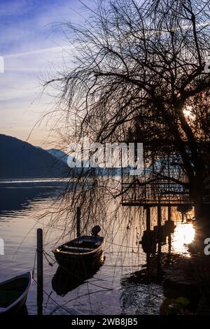 Tramonto sul Lago di Lugano di Morcote con barca e ristorante a sihouette in una soleggiata giornata invernale Foto Stock