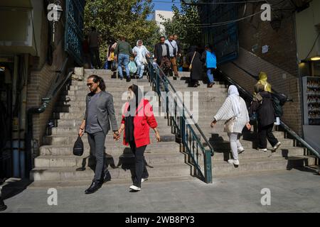 Un giovane uomo e una donna vestiti in modo intelligente camminano insieme tenendosi per mano nel centro storico di Teheran, Iran. Foto Stock