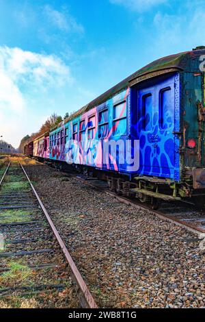 AS, Limburgo, Belgio. 17 dicembre 2023. Binari ferroviari in disuso della vecchia stazione ferroviaria, prospettiva angolare laterale della vecchia carrozza passeggeri con lato e rea Foto Stock