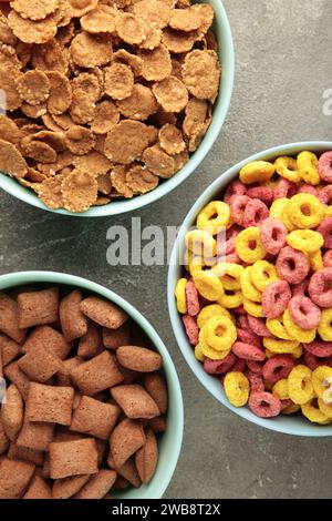 Varietà di cereali in ciotole blu, colazione veloce su sfondo grigio. Vista dall'alto Foto Stock