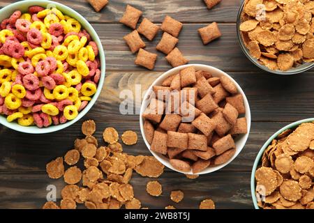 Varietà di cereali in ciotole blu, colazione veloce su fondo di legno marrone. Vista dall'alto Foto Stock