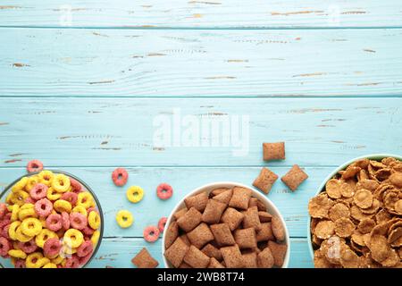 Varietà di cereali in ciotole blu, colazione veloce su sfondo di legno blu. Vista dall'alto Foto Stock