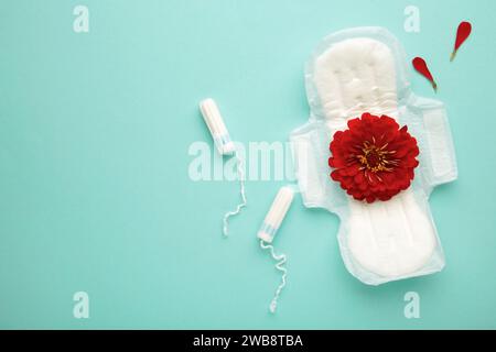Vista dall'alto delle coppette mestruali, tampone con fiore rosso su sfondo di menta. Vista dall'alto Foto Stock