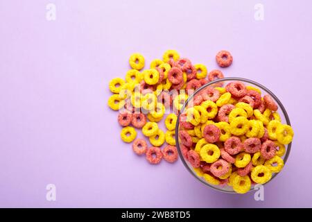 Cereali multicolori con fruttato su sfondo viola. Spazio vuoto per i testi. Foto Stock