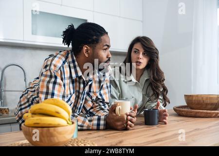 I colleghi di lavoro parlano durante la pausa pranzo nella cucina dell'ufficio. Donna comunica con una compagna di lavoro tenere tazze di caffè godere di una conversazione, discutere di lavoro o p Foto Stock