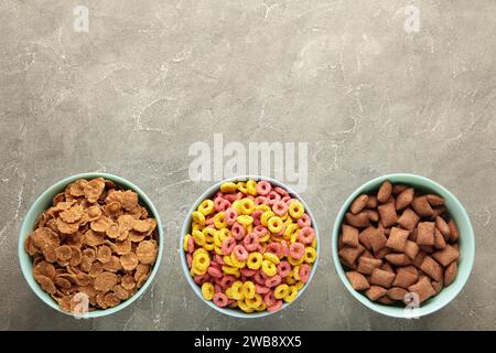 Varietà di cereali in ciotole blu, colazione veloce su sfondo di legno grigio. Vista dall'alto Foto Stock