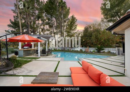 Una piscina di fronte ad un patio esterno coperto con un tetto e con mobili da patio Foto Stock