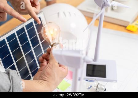 Giovane donna asiatica con pannello solare e lampadina, concetto di energia solare. Foto Stock