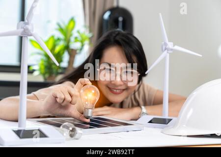 Giovane donna asiatica con pannello solare e lampadina, concetto di energia solare. Foto Stock