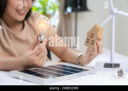 Giovane donna asiatica con pannello solare e lampadina, concetto di energia solare. Foto Stock