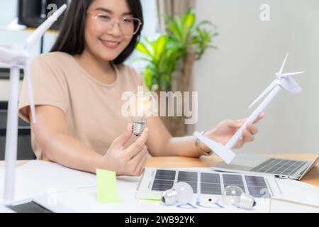 Giovane donna asiatica con pannello solare e lampadina, concetto di energia solare. Foto Stock