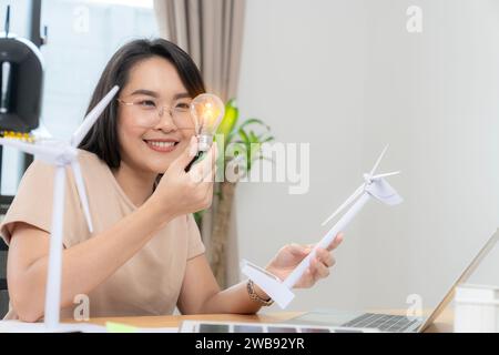 Giovane donna asiatica con pannello solare e lampadina, concetto di energia solare. Foto Stock