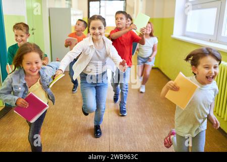 Ritratto di una ragazza felice che corre con compagni di classe nel corridoio durante la pausa Foto Stock