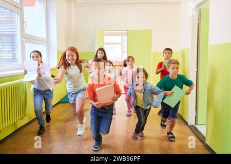Gruppo di bambini eccitati maschi e femmine che corrono nel corridoio durante la pausa a scuola Foto Stock