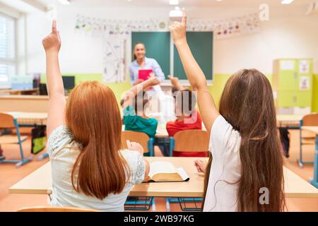 Vista posteriore delle studentesse che rispondono durante la lezione in classe a scuola Foto Stock