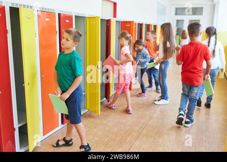 Gruppo di bambini delle scuole elementari nei loro armadietti nel corridoio durante la pausa Foto Stock