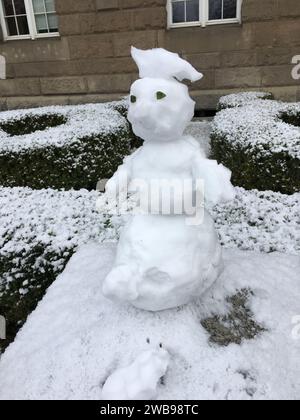 Un piccolo pupazzo di neve è migliorato su un palo di pietra. Versione mini. Inverno in Polonia. Foto Stock