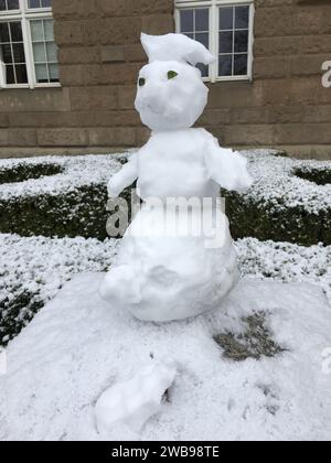 Un piccolo pupazzo di neve è migliorato su un palo di pietra. Versione mini. Inverno in Polonia. Foto Stock