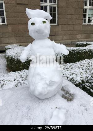 Un piccolo pupazzo di neve è migliorato su un palo di pietra. Versione mini. Inverno in Polonia. Foto Stock