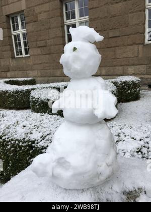 Un piccolo pupazzo di neve è migliorato su un palo di pietra. Versione mini. Inverno in Polonia. Foto Stock