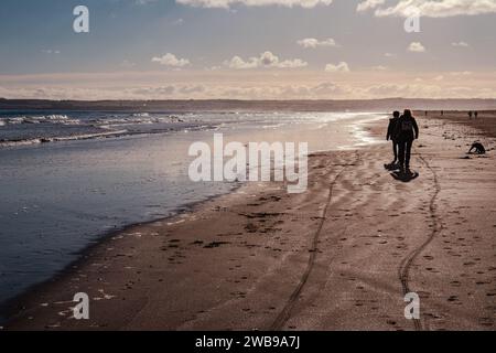 Persone retroilluminate che camminano lungo un'ampia distesa di spiaggia in un giorno d'inverno Tentsmuir Sands nell'estremo nord-est vicino a Tayport Fife Scozia Foto Stock