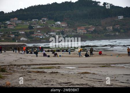 Numerosi volontari si sono recati sulle spiagge della Galizia per raccogliere pellet di plastica caduti su una barca utilizzando strumenti di base come imbuti, filtri, Foto Stock