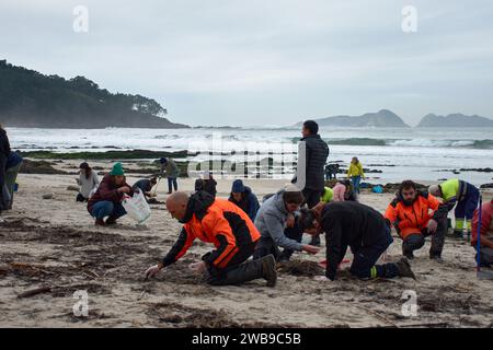 Numerosi volontari si sono recati sulle spiagge della Galizia per raccogliere pellet di plastica caduti su una barca utilizzando strumenti di base come imbuti, filtri, Foto Stock