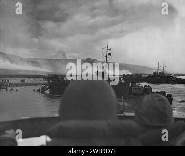 OMAHA BEACH, NORMANDIA, FRANCIA - 06 giugno 1944 - due marinai della US Navy (in primo piano) navigano vicino a Omaha Beach durante le prime fasi dell'invasione di N Foto Stock