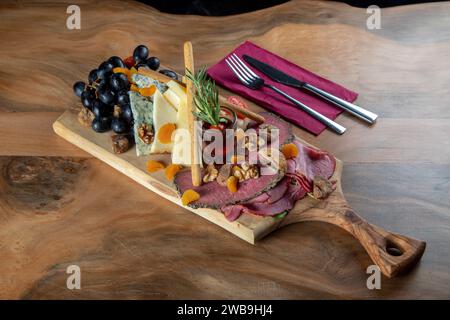 Piatto di antipasti con carne affumicata, formaggio cheddar e uva nera Foto Stock