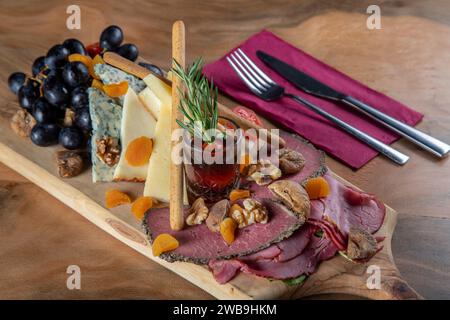 Piatto di antipasti con carne affumicata, formaggio cheddar e uva nera Foto Stock