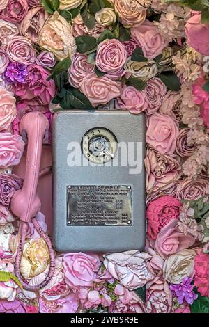 vecchio telefono di strada decorato con fiori Foto Stock