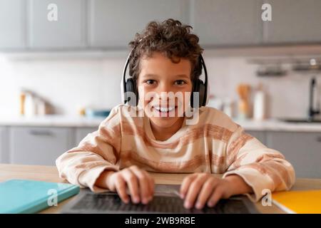 Ripresa POV di Little Black Boy in cuffia utilizzando il laptop a casa Foto Stock