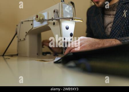 Processo di cucitura della cinghia in pelle. vecchio uomo le mani dietro la cucitura. Workshop di pelle. vintage tessili industriali di cucitura Foto Stock