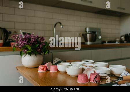 Ampia scelta di rivestimenti per cupcake in diversi colori con teglia per muffin e frusta metallica Foto Stock