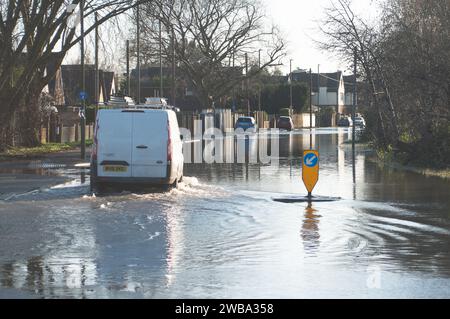 Staines upon Thames, Surrey, Regno Unito. 9 gennaio 2024. Un pulmino attraversa le acque alluvionali in una strada chiusa a Staines upon Thames, Surrey. Le inondazioni del Tamigi hanno lasciato diversi giardini sott'acqua a Staines upon Thames nel Surrey. Credito: Maureen McLean/Alamy Live News Foto Stock