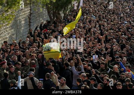 Khirbet SELM, Libano. 9 gennaio 2024. I sostenitori pro-iraniani di Hezbollah portano la bara del comandante supremo del partito Wissam Tawail durante la sua processione funebre nel villaggio libanese meridionale di Khirbit Selem. Tawil è il comandante di Hezbollah di grado più alto ad essere ucciso dopo l'eruzione del conflitto transfrontaliero tra Israele e Hezbollah in Libano l'8 ottobre, e il secondo assassinio di alto profilo avvenuto in Libano in due settimane. Crediti: Marwan Naamani/dpa/Alamy Live News Foto Stock