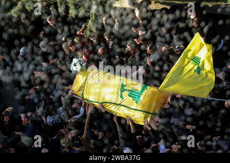 Khirbet SELM, Libano. 9 gennaio 2024. I sostenitori pro-iraniani di Hezbollah portano la bara del comandante supremo del partito Wissam Tawail durante la sua processione funebre nel villaggio libanese meridionale di Khirbit Selem. Tawil è il comandante di Hezbollah di grado più alto ad essere ucciso dopo l'eruzione del conflitto transfrontaliero tra Israele e Hezbollah in Libano l'8 ottobre, e il secondo assassinio di alto profilo avvenuto in Libano in due settimane. Crediti: Marwan Naamani/dpa/Alamy Live News Foto Stock