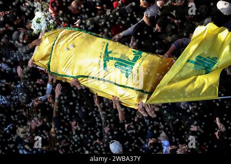 Khirbet SELM, Libano. 9 gennaio 2024. I sostenitori pro-iraniani di Hezbollah portano la bara del comandante supremo del partito Wissam Tawail durante la sua processione funebre nel villaggio libanese meridionale di Khirbit Selem. Tawil è il comandante di Hezbollah di grado più alto ad essere ucciso dopo l'eruzione del conflitto transfrontaliero tra Israele e Hezbollah in Libano l'8 ottobre, e il secondo assassinio di alto profilo avvenuto in Libano in due settimane. Crediti: Marwan Naamani/dpa/Alamy Live News Foto Stock