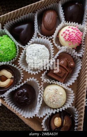 Caramelle fatte a mano. Cioccolato bianco e fondente con noci in confezione regalo. Vista dall'alto, primo piano. Sfondo di caramelle fatte a mano. Foto Stock