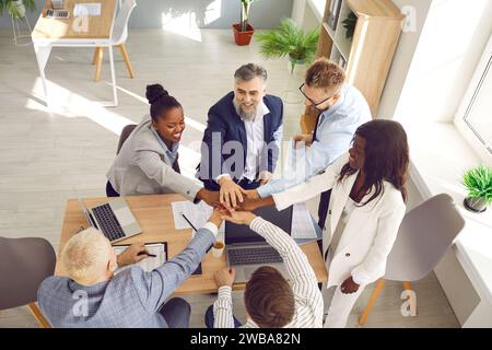 Uomini d'affari motivati che mettono insieme le mani, vista dall'alto Foto Stock