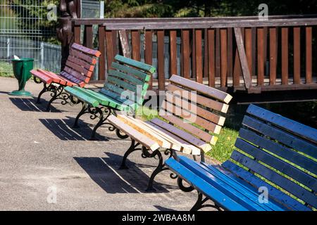 Panchine colorate in legno con gambe in metallo fuso nel parco Foto Stock