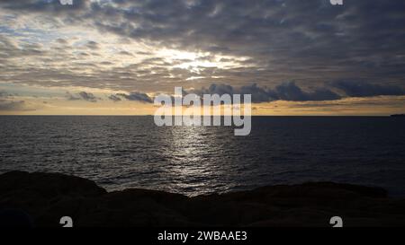 Tramonto sul mare in Italia con sole dietro le nuvole Foto Stock