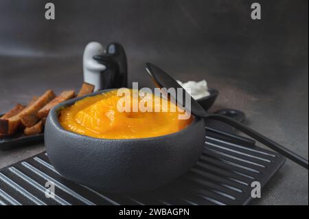 Deliziosa zuppa di zucca con panna spessa su un tavolo rustico di legno scuro con crostini. Vista laterale. Copia spazio Foto Stock