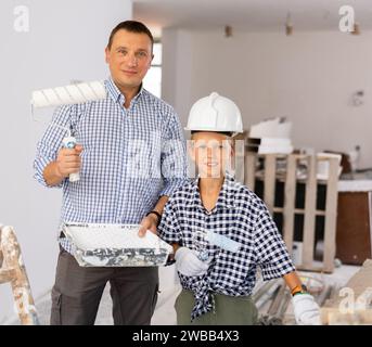 Ritratto di ragazzo e padre positivi con rulli di vernice Foto Stock