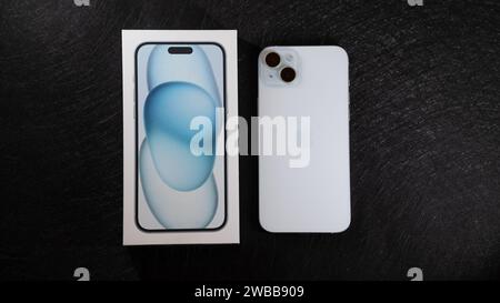 Jurmala, Lettonia - 09 01 2024: Su tavolo nero, nuovo smarphone Apple iPhone 15 Plus in colore blu e scatola bianca. Foto Stock